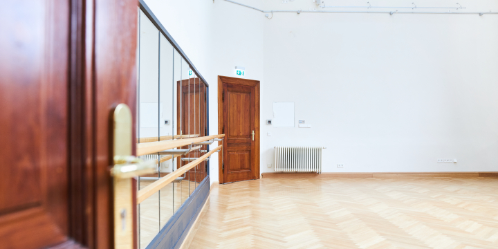 Blick in einen Raum von der hölzernen Eingangstür aus, wobei die Blickrichtung auf eine verspiegelte Wand mit Balletstange fällt.  ©JenaKultur, Karoline Krampitz